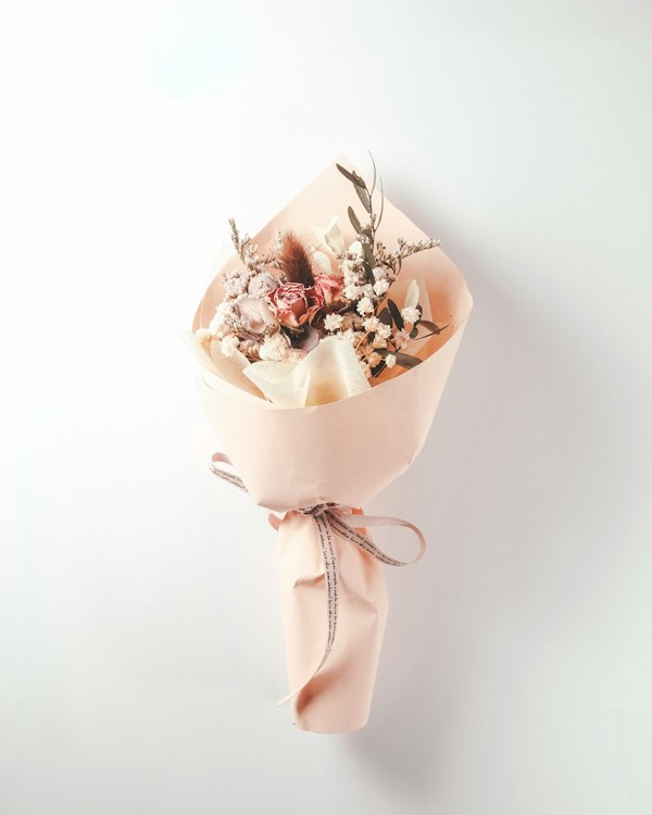 Dried flower bouquet in shades of pink, wrapped in pink paper
